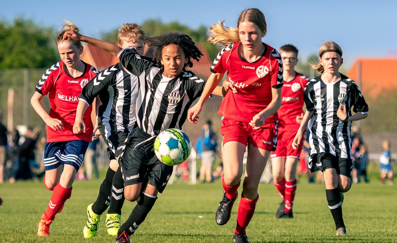 Jongeren spelen samen voetbal op een groen veld